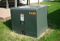 一个绿色的护垫式变压器箱，显示在一个家庭的后院.  