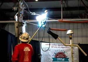在高压电力演示中，一名穿红衬衫的线路员用玻璃纤维棒制造电弧.